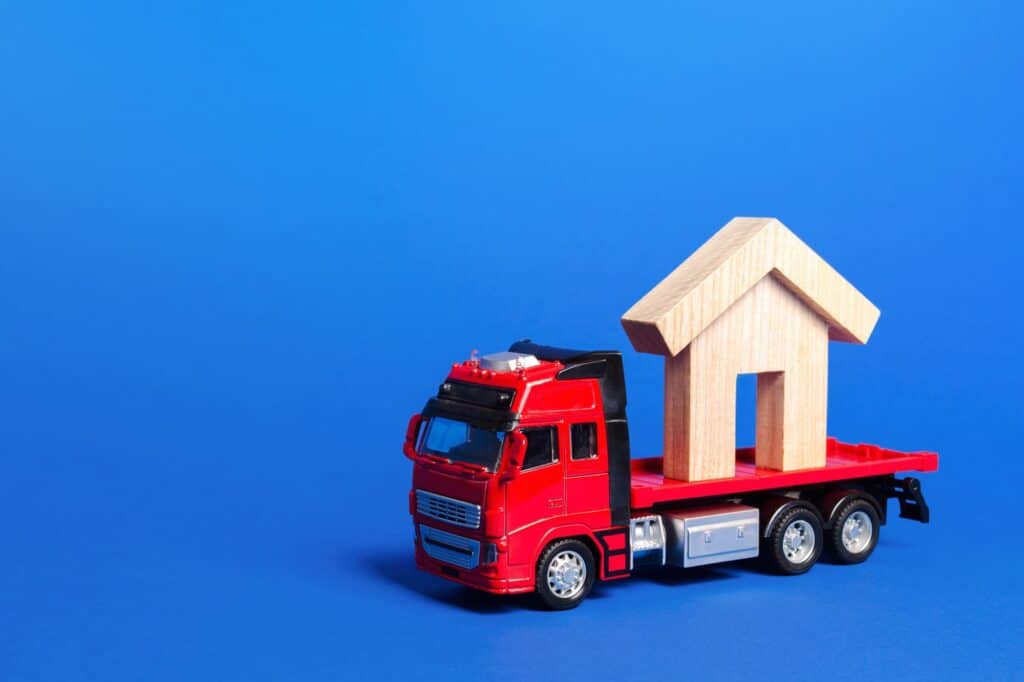 A wooden house figurine at the back of the truck in the concept of house move