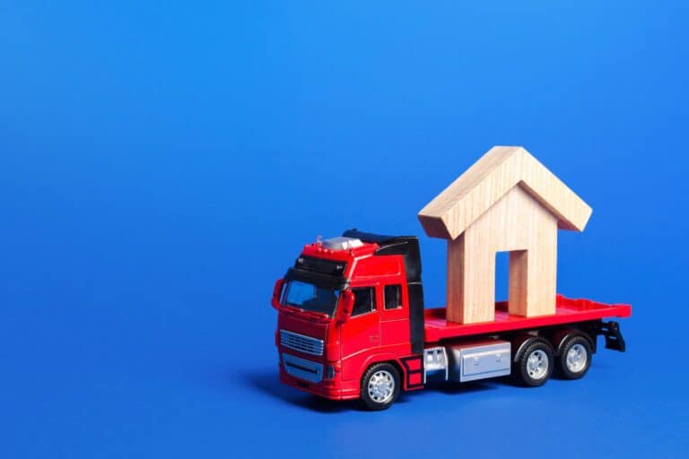 A wooden house figurine at the back of the truck in the concept of house move