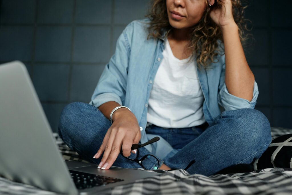 A woman on her bed is researching for Ealing man and van companies through her laptop.