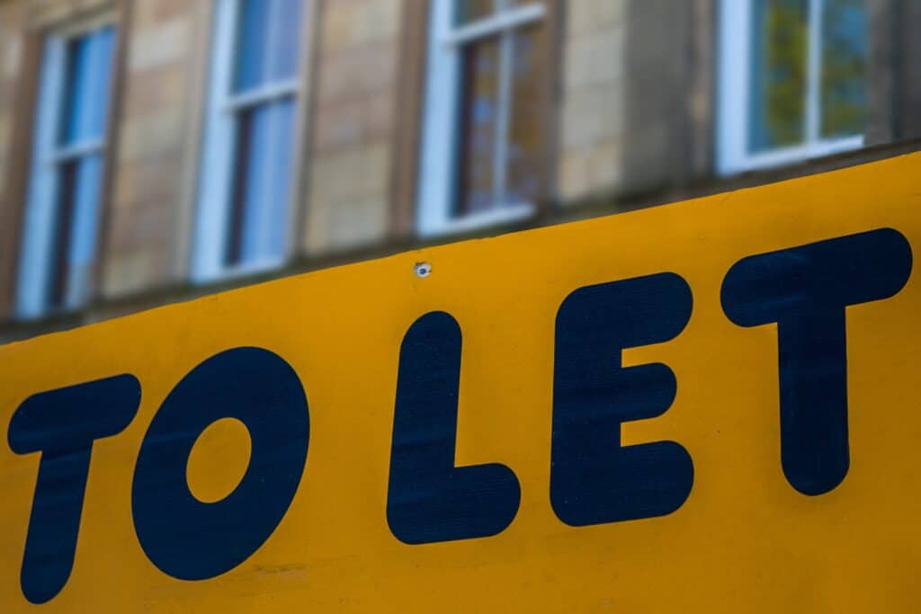 A 'To Let' sign with a residential building in the background in the concept of affordable housing in Ealing.