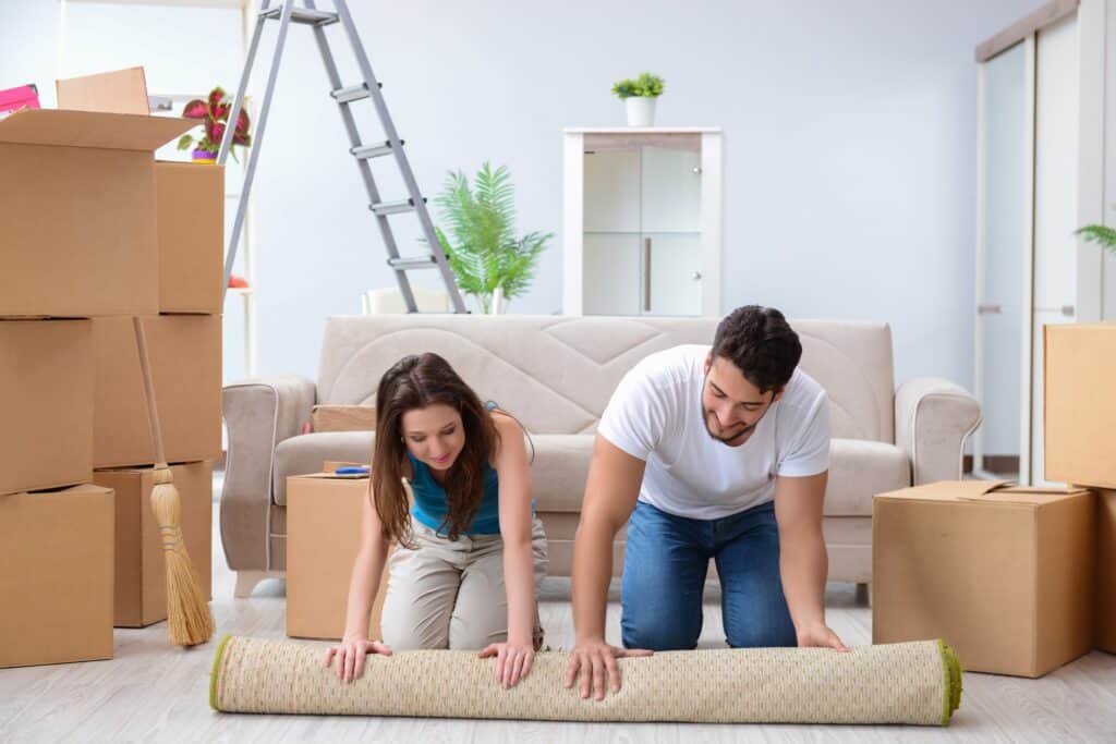 A young couple is unpacking at their new house in the concept of 'how to save money when moving to Ealing'.