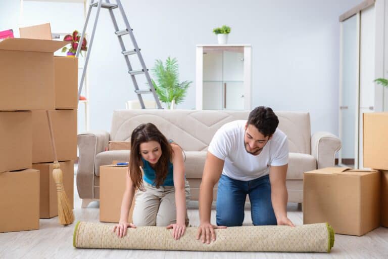 A young couple is unpacking at their new house in the concept of 'how to save money when moving to Ealing'.