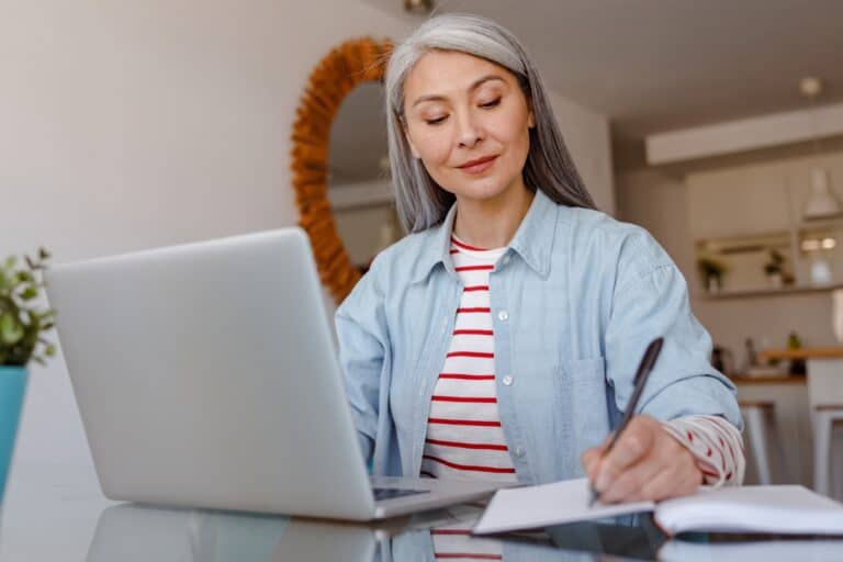A woman in the dining area in front of the laptop is creating a moving checklist in the concept of 'How to Create a Moving Checklist'.