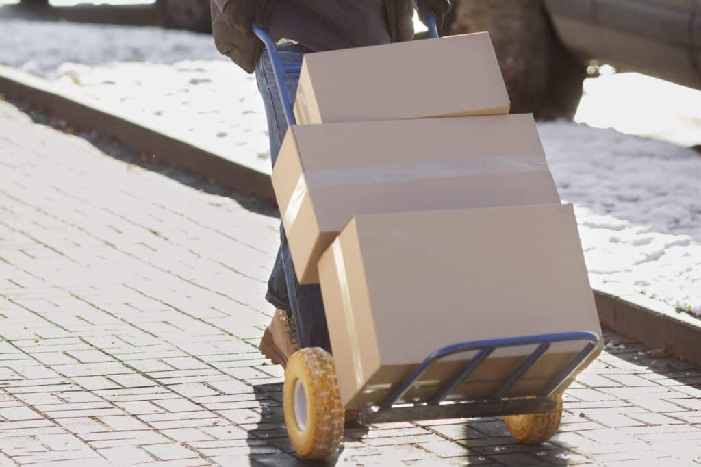 Cropped image of a mover pushing a cart with a stack of boxes