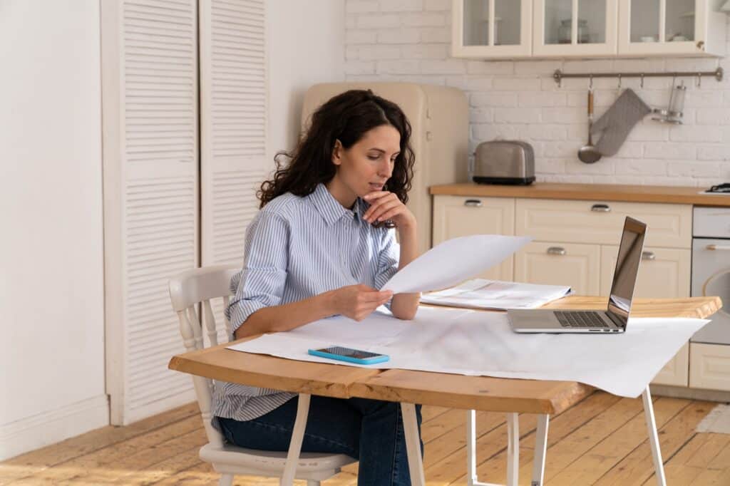 A woman reviews the home removals' policies in her dining area