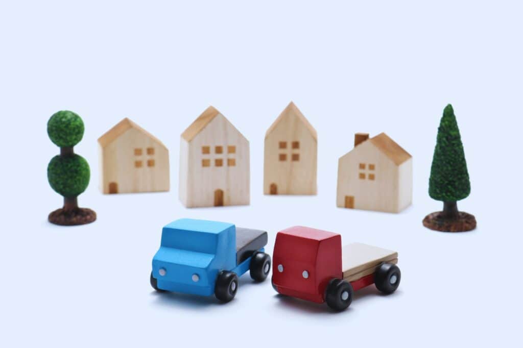 Toy trucks and wooden house figurines in the concept of 'How to Choose the Best Home Removals Company'.